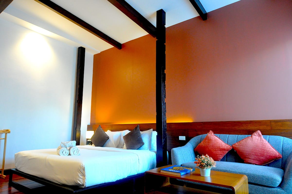 A hotel room with a bed, a blue sofa, and a wooden coffee table.