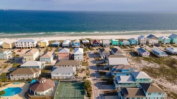 Zona residencial costera con casas, cancha de tenis y playa.