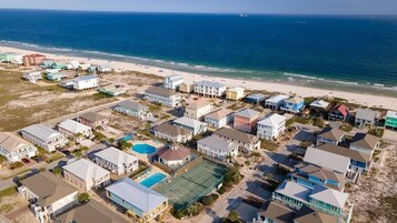 Zona residencial costera con casas, una playa y una cancha de tenis.
