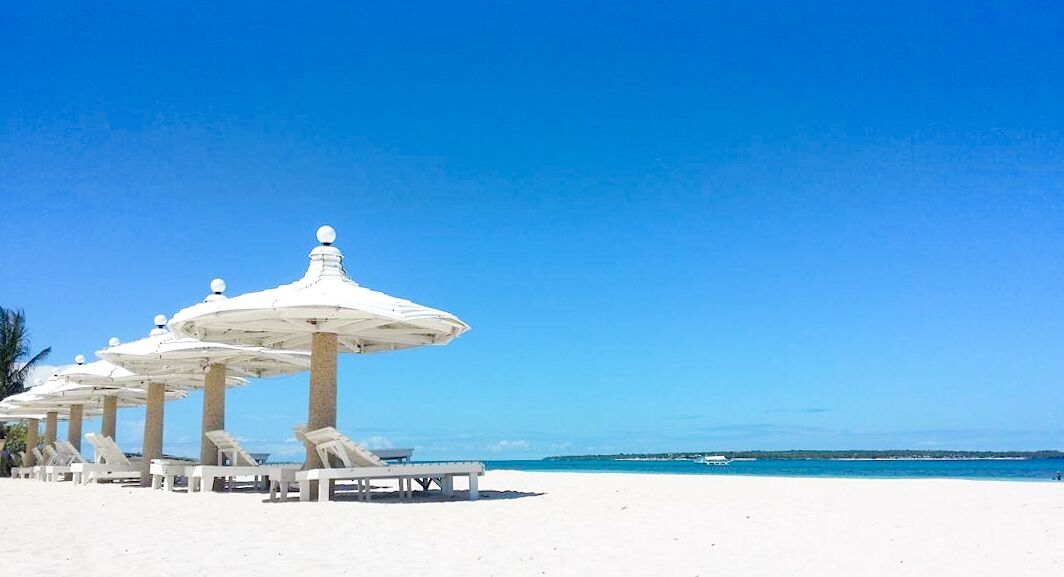 A beach with white umbrellas and lounge chairs.