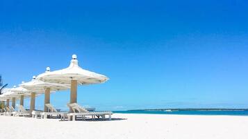 A beach with white umbrellas and lounge chairs.