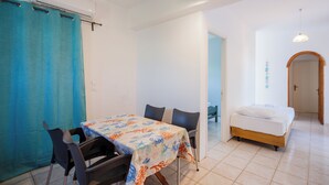 Ein Zimmer mit Esstisch, Stühlen, einem Bett und einem Badezimmer mit Duschvorhang.