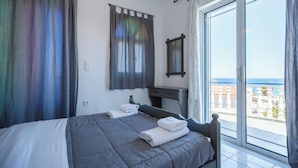 Ein Schlafzimmer mit Bett, Schreibtisch und Meerblick.