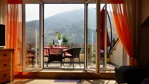 Ein Zimmer mit einer Schiebetür zu einem Balkon, der einen Tisch und Stühle, eine Kommode und ein Bett bietet.