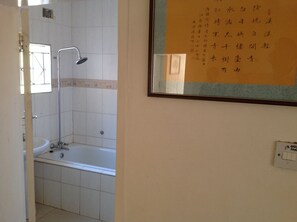 Une salle de bain avec une baignoire, une douche et un lavabo. Un tableau encadré est accroché au mur.