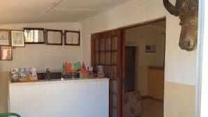 A reception desk with framed certificates, a clock, and flags. - Standard Way Lodge (Livingstone)
