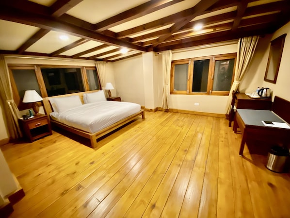 Un dormitorio con una cama de madera, dos mesitas de noche, un escritorio y una ventana con cortinas.