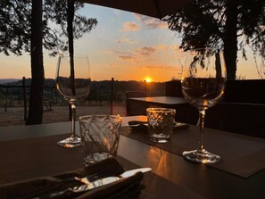 Un tavolo imbandito per due, con calici di vino e una candela, con vista sul tramonto.