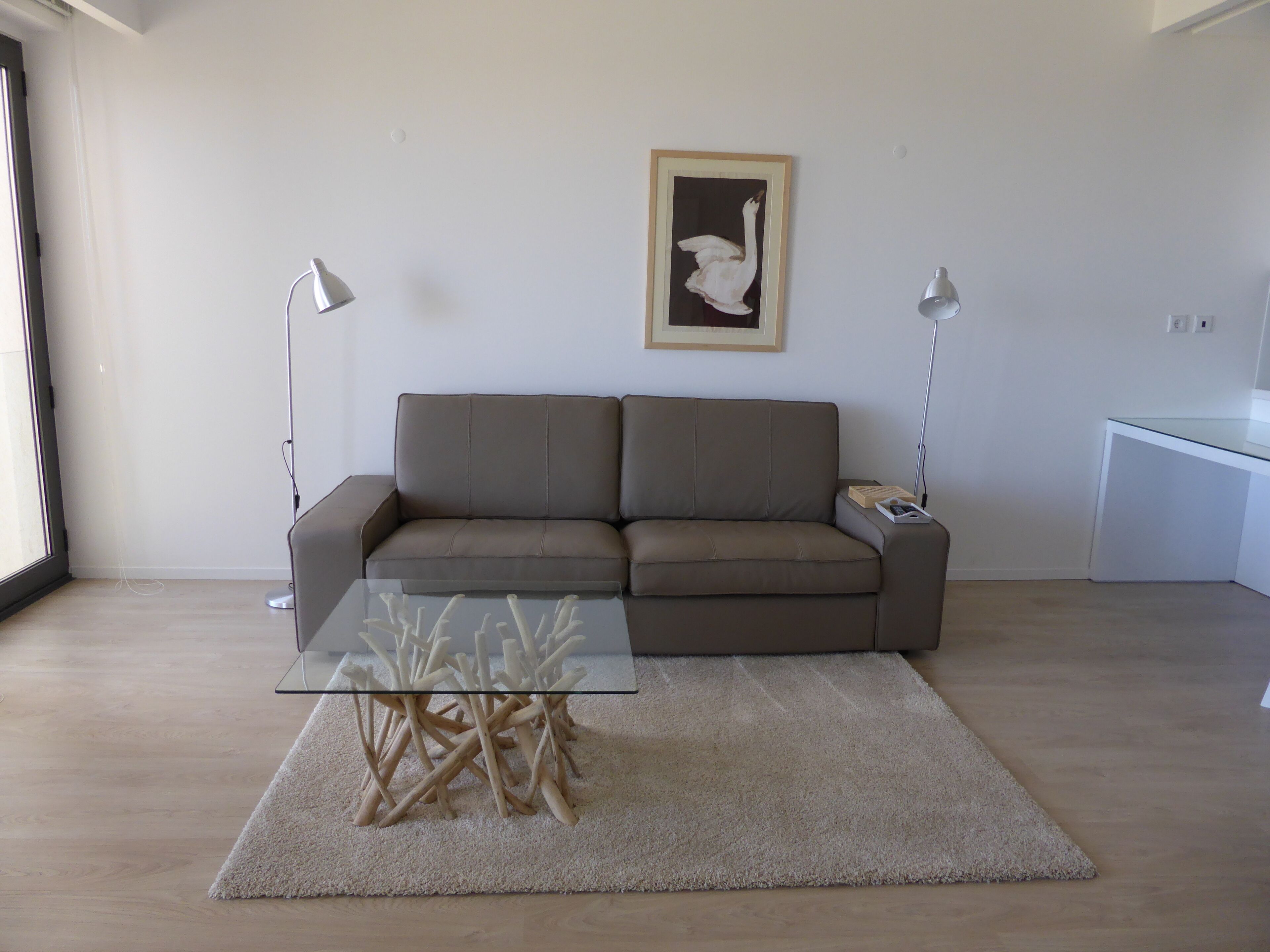 Un saló modern amb un sofà marró, una taula de centre de vidre i una obra d'art emmarcada a la paret.