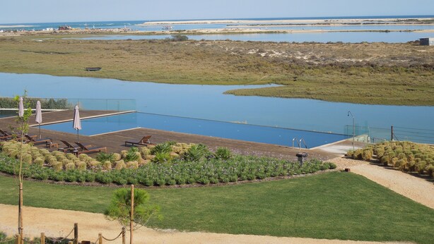 A pool area with lounge chairs and a small garden. - A beautiful one bedroom apartment - right on the waterfront in the Ria Formosa. (Fuseta)