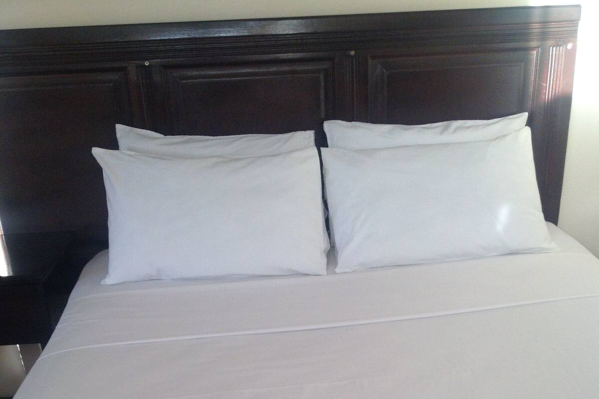 A neatly made bed with a wooden headboard and white bedding.
