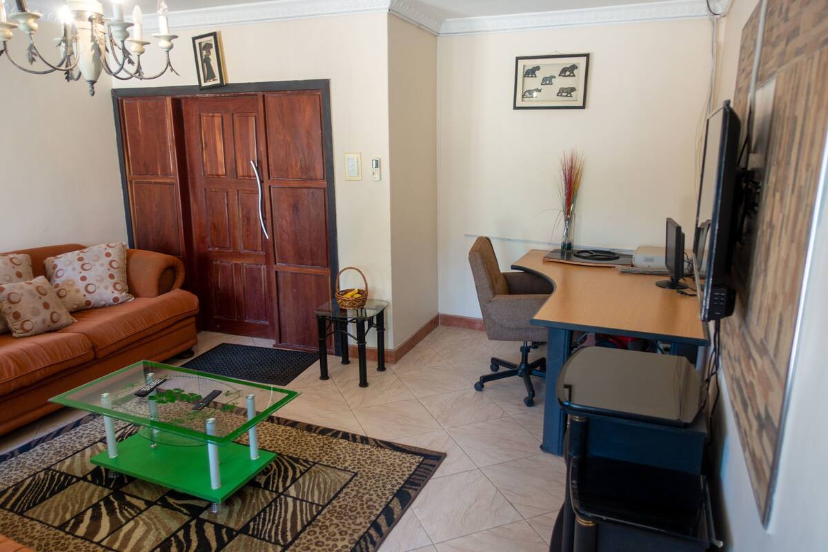 A living room with a sofa, coffee table, and a desk with a computer.