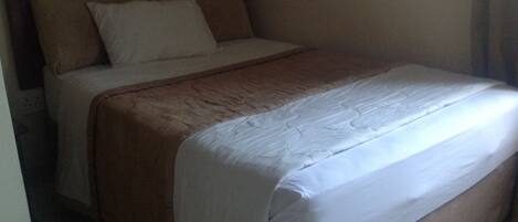 Una cama con cabecera de madera, ropa de cama blanca y una manta marrón.