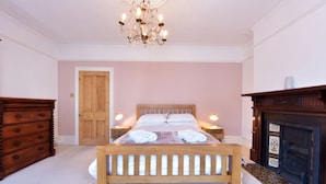 Un dormitorio con cama de madera, lámparas de noche, cómoda de madera y chimenea.