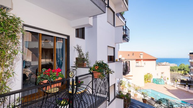 A balcony with potted plants, a bicycle, and a view of the sea. - Marino Suite Sorrento (Sorrento)