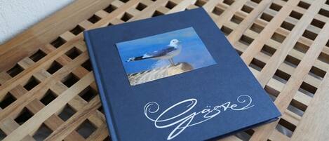 A book with a seagull photo and the word "Gäste" on a wooden lattice table.