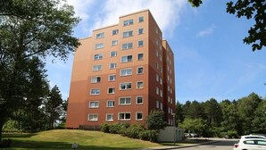 A multi-story building with a red brick facade, multiple windows, and a parking lot with a few cars. - Welcome to our "Möwennest" apartment in a prime location! WIRELESS INTERNET ACCESS (Sankt Peter-Ording)