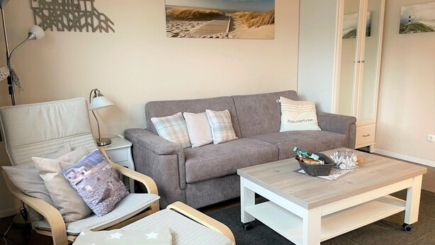 A cozy living room with a grey sofa, a wooden coffee table, and a white cabinet. - Welcome to our "Möwennest" apartment in a prime location! WIRELESS INTERNET ACCESS (Sankt Peter-Ording)