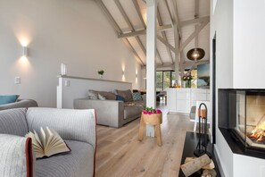 En moderne stue med pejs, sofa, sofabord og spiseplads.