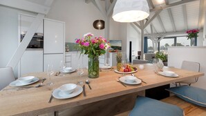 A dining area with a wooden table, white plates, and a vase of flowers. - AS1C - Old barn (AS) at c a l l s e n - appartements (Ummanz)