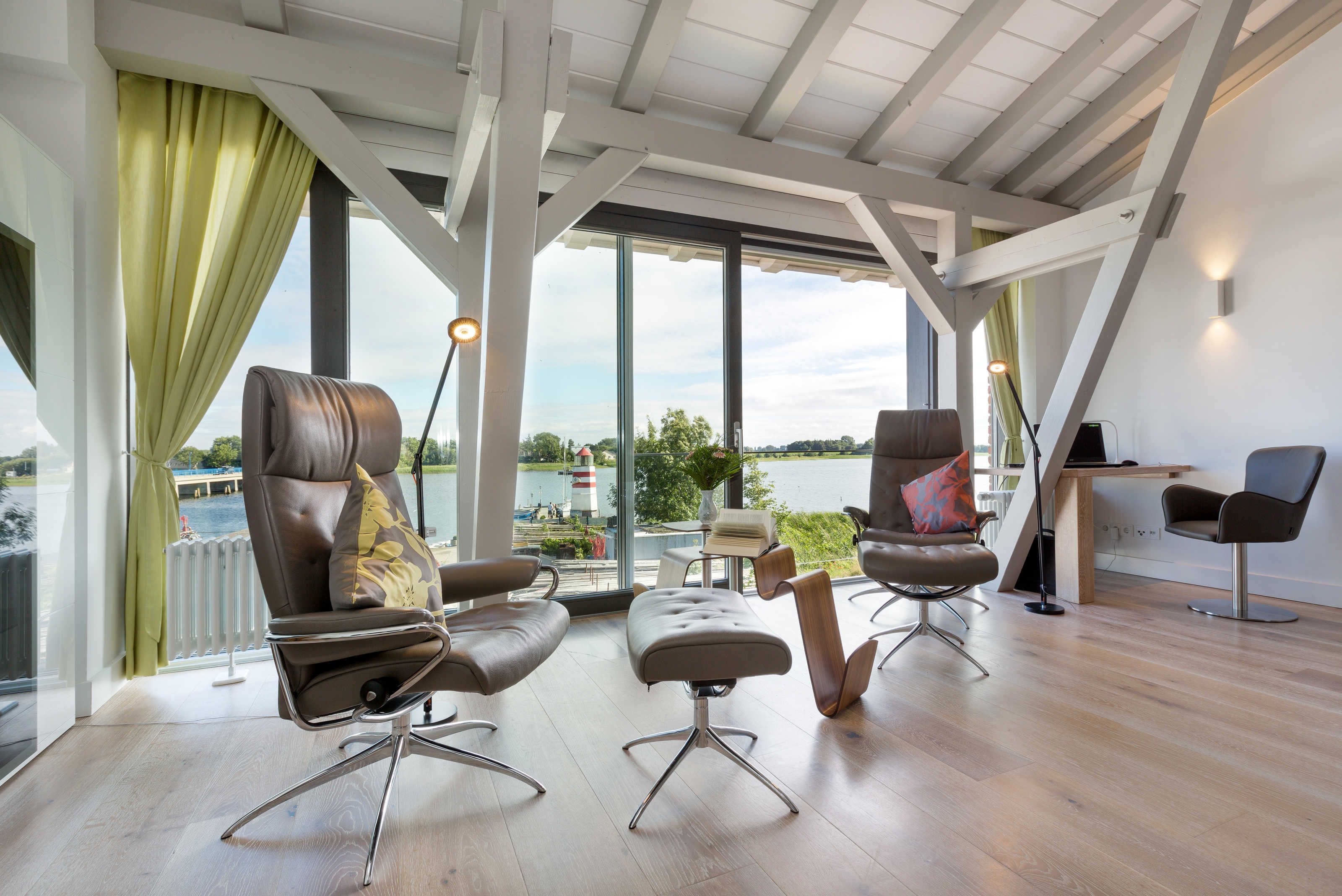 A modern interior with large windows, a view of a body of water, and a dining area.