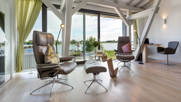 A modern interior with large windows, a view of a body of water, and a dining area. - AS1C - Old barn (AS) at c a l l s e n - appartements (Ummanz)