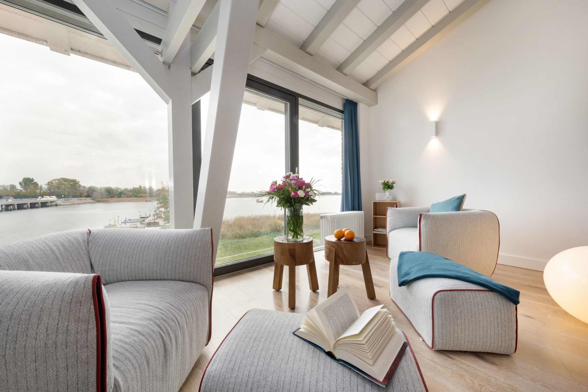 Un salon moderne avec une grande fenêtre, un canapé, une table basse et une bibliothèque.