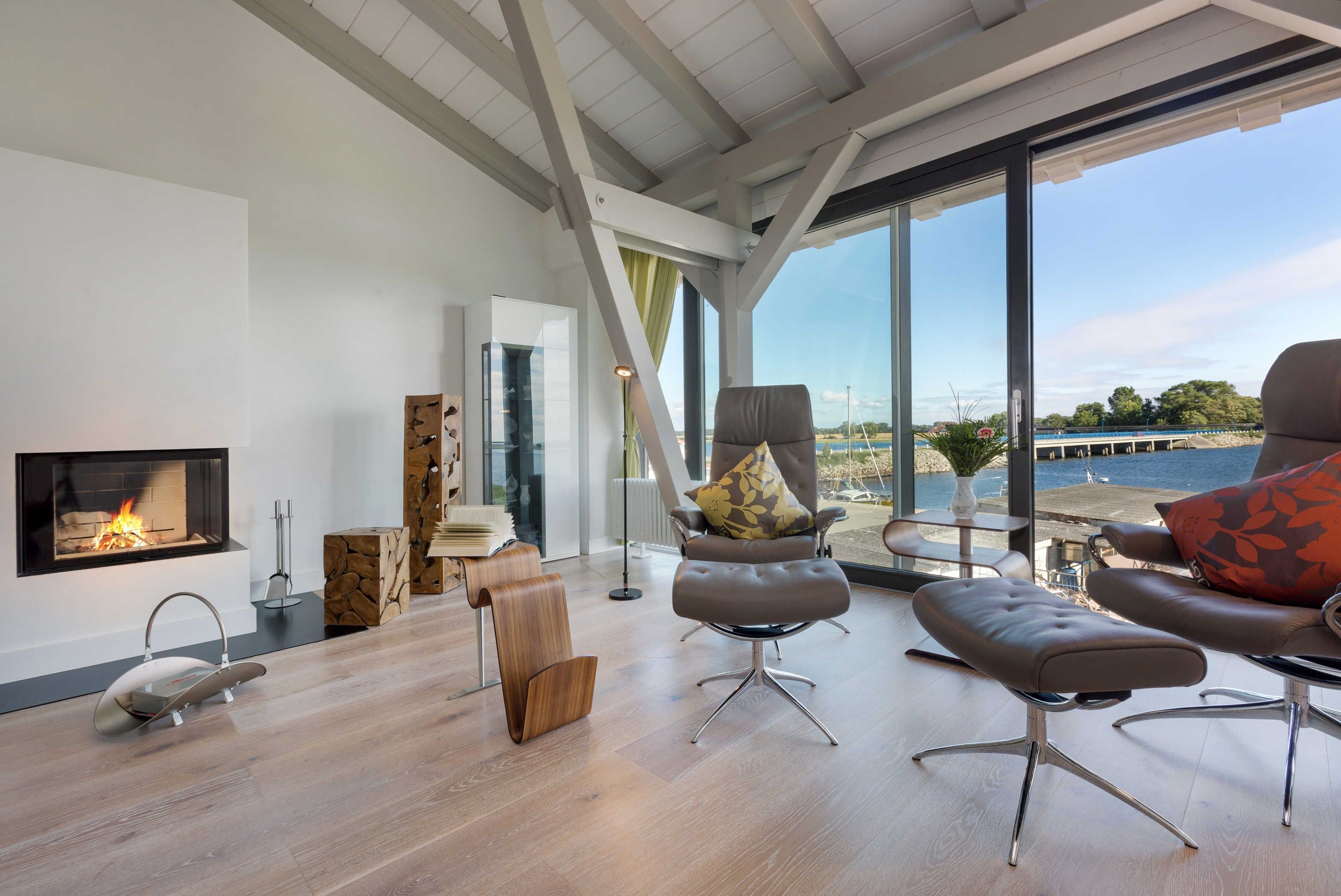 A modern living room with a fireplace, large windows, and a view of the water.