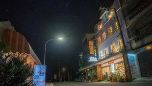 Una calle de noche con un restaurante a la derecha.