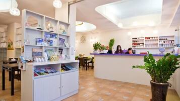 A reception area with a counter, shelves with magazines, and a potted plant.