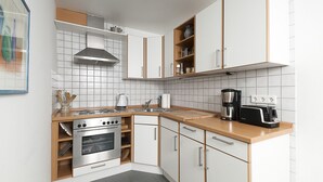 Eine moderne Küche mit weißen Schränken, einem Edelstahlbackofen, einer Kaffeemaschine und einem Toaster.