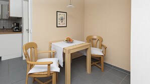 Ein kleiner Essbereich mit zwei Holzsesseln, einem Tisch mit weißer Tischdecke und einer Obstschale auf dem Tisch.