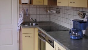 A kitchen with yellow cabinets, a sink, a stove, and a coffee maker.