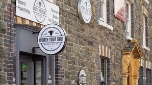 Un edificio de piedra con varios carteles que anuncian un restaurante llamado 'Worth Your Salt', que ofrece café, postres y eventos privados.