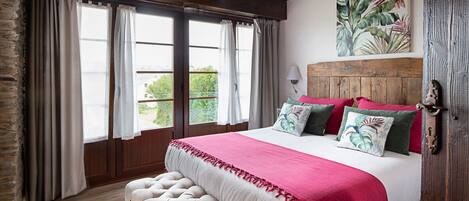 Un dormitorio con una cama grande, cabecera de madera y vistas al exterior.