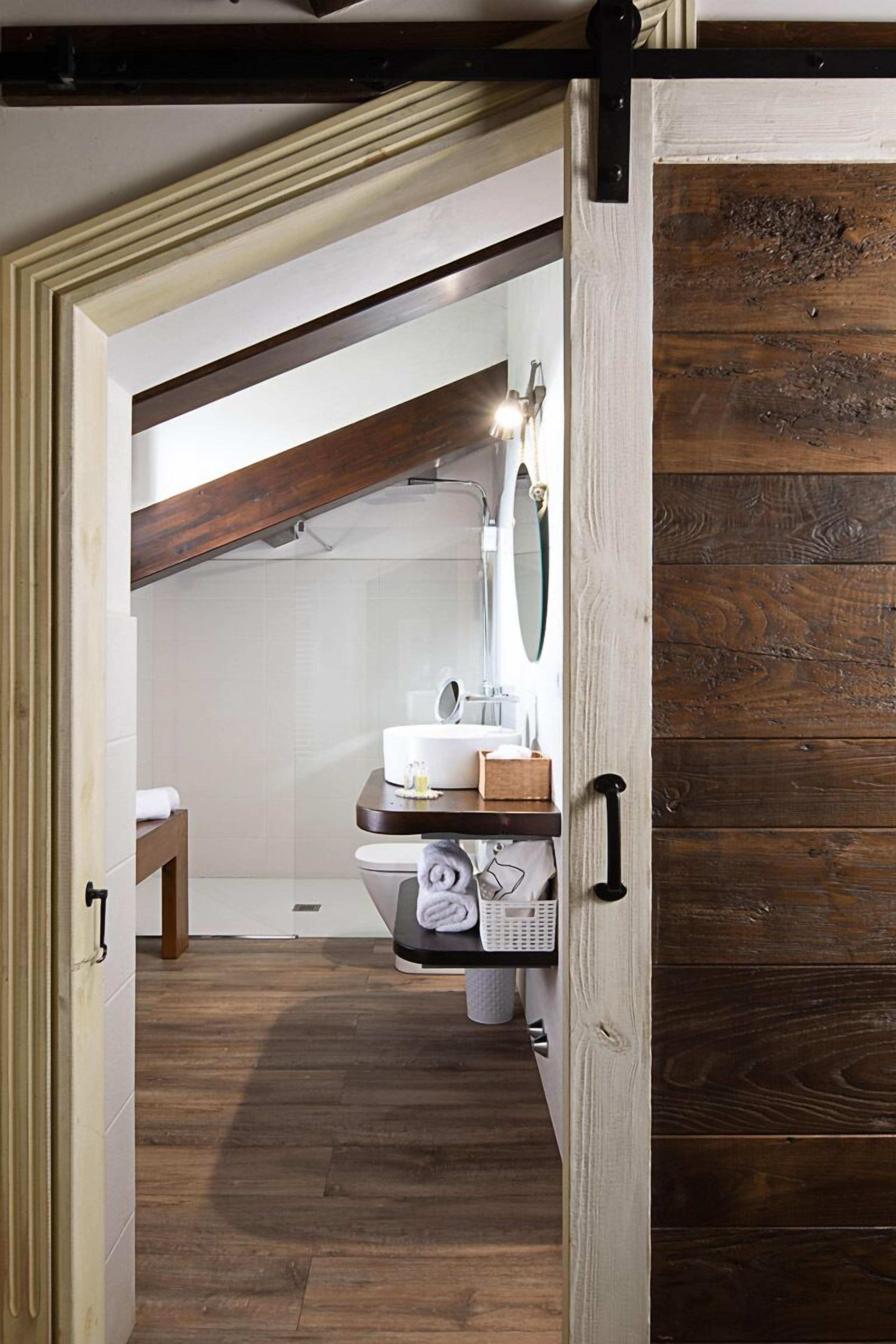 Une salle de bain avec un plancher en bois, un lavabo blanc, un miroir et un porte-serviettes.