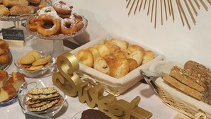 Un bufé con diversas opciones de panadería, incluyendo pasteles y galletas, dispuesto en una mesa con un espejo decorativo con diseño de sol arriba.