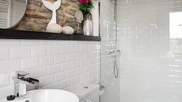 A bathroom with a white sink, toilet, and shower.