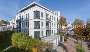 A multi-story residential building with balconies, large windows, and a paved pathway.