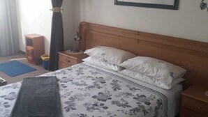 A bedroom with a bed, a nightstand, a framed picture on the wall, and a window with curtains. - Beach Mansion 1 (Margate)