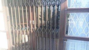 A building with a metal gate, a window with a diamond pattern, and a tiled floor. - Beach Mansion 1 (Margate)