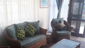 A living room with a sofa, two armchairs, a coffee table, and a patterned rug. - Beach Mansion 1 (Margate)