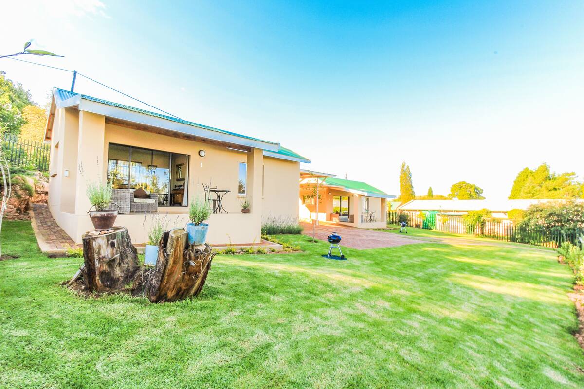A modern house with a well-maintained lawn, a barbecue grill, and a patio area.