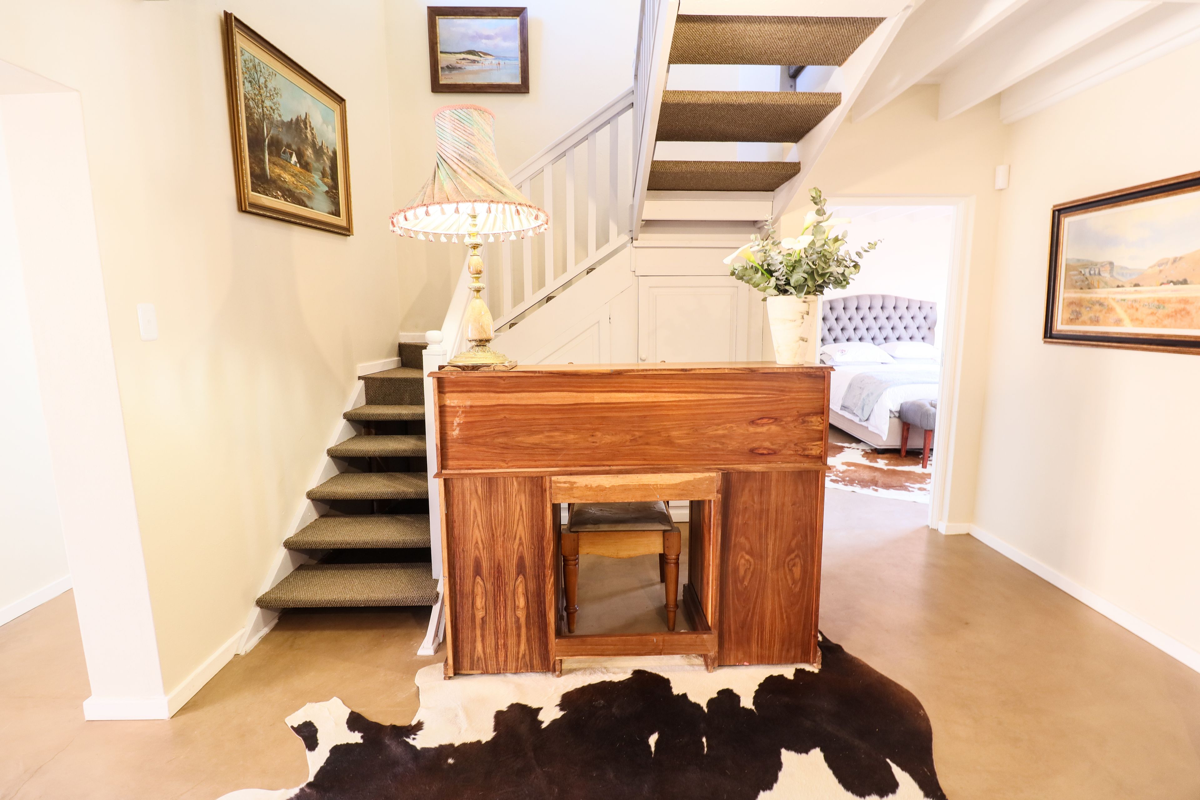 A staircase with a wooden finish, a small wooden table with a lamp, and a cowhide rug on the floor.