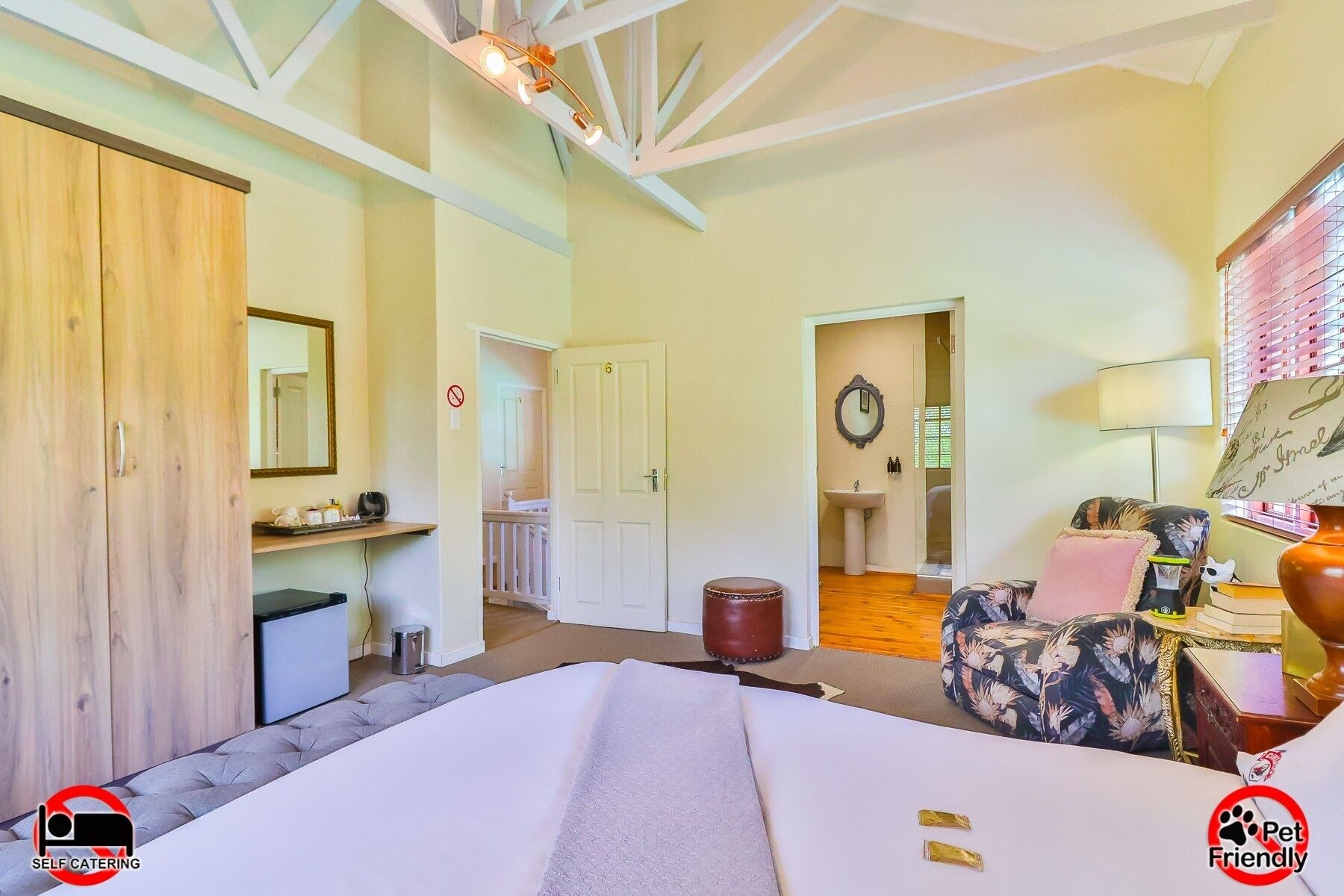 A room with a bed, a desk, a chair, a mirror, a sink, and a door.