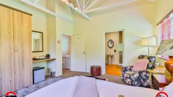 A room with a bed, a desk, a chair, a mirror, a sink, and a door.