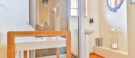 Habitación con cocina propia, ventana con marco de madera, lavamanos, espejo y cartel que indica que admite mascotas.