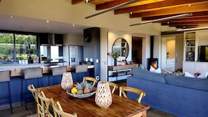A modern kitchen with a dining area, a fireplace, and a living room with a sofa. - Oubaai Villa  (Herolds Bay)