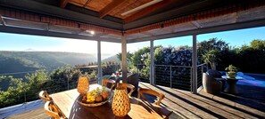 Una terraza de madera con una mesa lista para comer, con vistas a un paisaje montañoso.