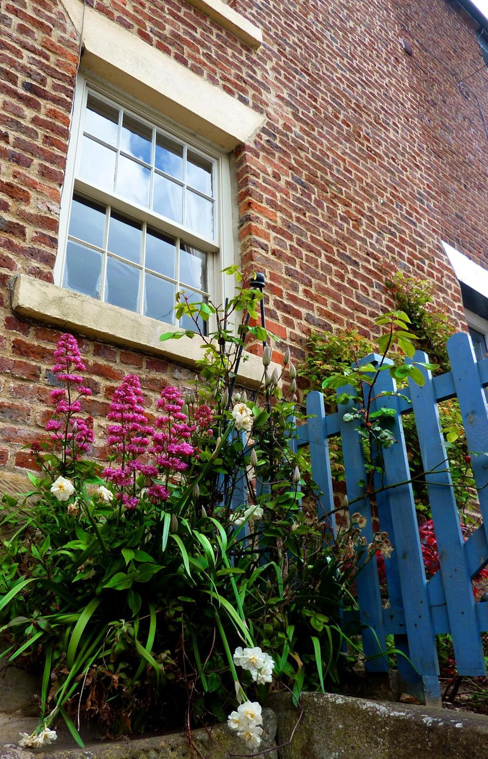A brick building with a white window and a blue gate.